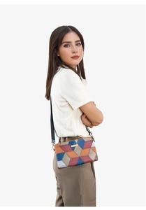Detail view of multicolored geometric crossbody bag with knit strap on a model