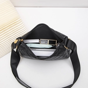 Black quilted bow bag with gold hardware showing inner storage space and wide strap
