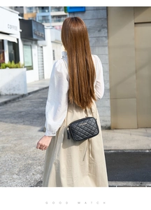 Detail of black quilted crossbody bag with gold chain strap and stylish side tassel charm