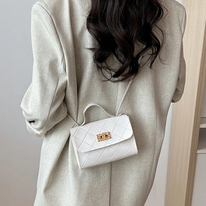 Classic white quilted crossbody bag with gold twist lock worn by a model in a grey suit
