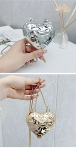 Dettaglio di pochette a forma di cuore in metallo argento e oro con texture martellata