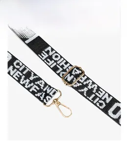 Detail of black and white strap with gold metal buckles and adjustable hardware