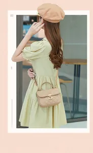 Detailed view of beige quilted leather bag with gold clasp shown on a model