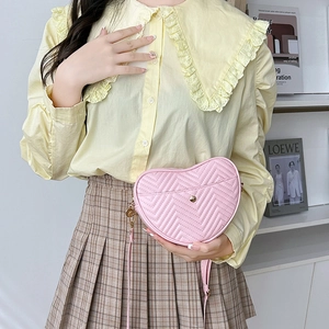 Pink heart-shaped crossbody bag with chevron quilting and delicate adjustable shoulder strap