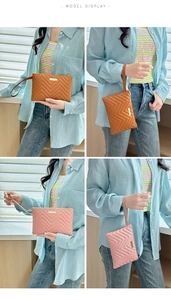 Detail of quilted wave pattern clutch with gold metal plate and wrist strap accessory