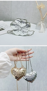 Dettaglio di mini borse in metallo a forma di cuore e fiore con elegante catena a serpente