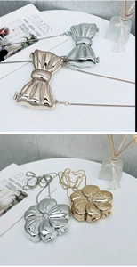 Dettaglio di mini pochette metalliche a forma di fiocco e fiore in oro e argento