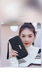 Detail of black quilted long wallet featuring double zippers and a gold metal accent