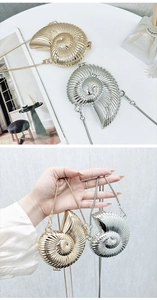 Detailed view of metallic nautilus shell clutch bag with detachable chain strap