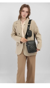 Detail of black quilted crossbody bag set with a small round pouch on a wide strap