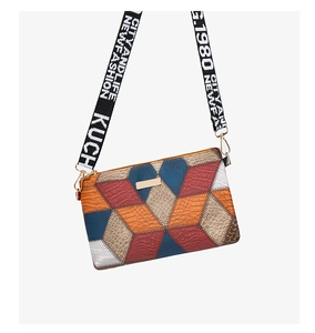 Close-up of geometric patchwork textures and metal tag on colorful crossbody bag