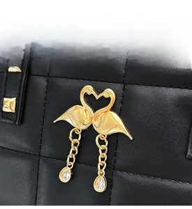 Detail of black quilted leather bucket bag featuring gold swan heart pendant and chain