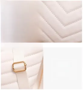 Detail of white V-quilted leather texture and golden metal buckle on the bucket bag