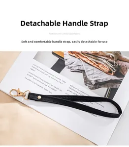 Detail of detachable black wristlet strap with gold lobster clasp on white magazine