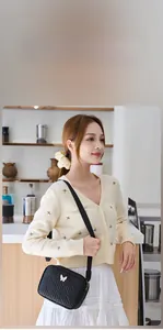 Détail du sac bandoulière en PU noir avec texture tissée et boucle papillon dorée