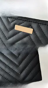 Detail of V-shaped quilted black leather texture with gold metal plate and zipper