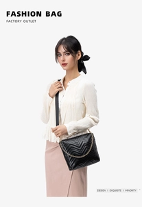 Detail of black quilted crossbody bag with V-shaped texture and gold chain strap