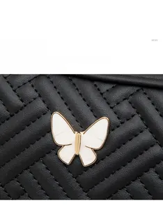 Détail du sac photo en cuir matelassé noir avec ornement de papillon en émail blanc