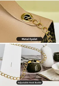 Close-up of golden chain strap and metal grommets on a beige monogram handbag