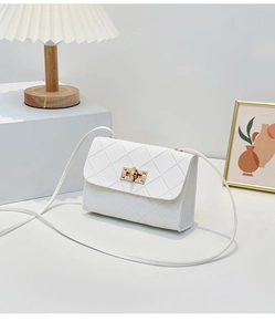 Detailed view of the quilted texture and golden rectangular twist lock on a white crossbody bag