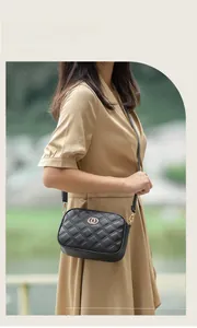 Detail of black quilted crossbody bag with golden hardware and interlocking rings buckle