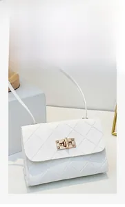 Close-up of white crossbody bag with quilted stitching and gold rectangular twist lock
