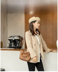 Close-up of a brown monogram patterned handbag with gold hardware on a female model