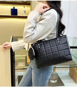 Detail of black quilted tote bag with detachable coin purse and gold rivet accents