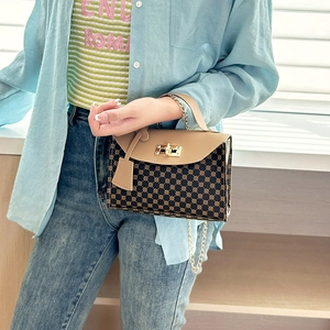 Retro patterned shoulder bag with gold chain strap and turn-lock on blue shirt background