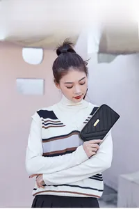 Detail of black quilted leather clutch with gold metal plate and secure zipper closure