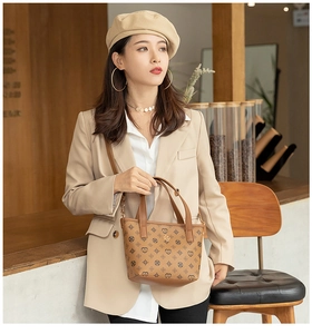 Detail of brown monogram handbag featuring gold hardware styled with an elegant outfit