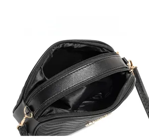 Detailed internal view of black wave-quilted camera bag with double gold zip compartments