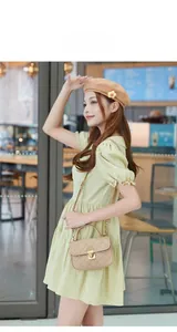 Quilted crossbody bag in beige leather with golden twist lock shown on a model
