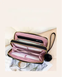 Détail d'une pochette matelassée à double zip avec fentes pour cartes et doublure rose tendre