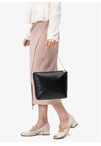 Detail shot of black chevron quilted chain bag worn by a model in a side profile view