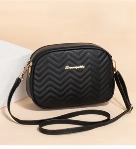 Detail shot of black chevron quilted texture and golden logo on the square crossbody bag