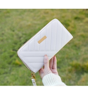 Close-up of white quilted leather long wallet with golden metal plate and wrist strap