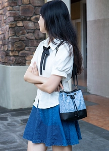 Detail der blauen Jacquard-Beuteltasche mit floralem Muster und schwarzem Lederbesatz
