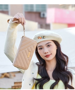 Detail showing beige long wallet with chevron quilting and golden metal hardware