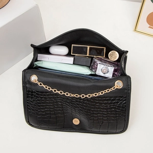 Black crocodile embossed crossbody bag with gold chain showing internal storage capacity