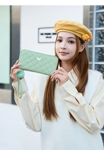 Détail du portefeuille matelassé vert clair avec breloque papillon et pompon en peluche