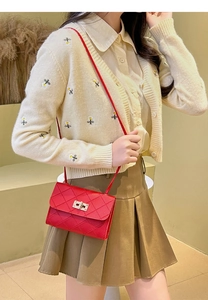 Detailed close-up of red quilted crossbody bag featuring a golden twist-lock closure