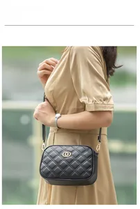 Elegant black quilted crossbody bag with gold circular buckle worn by a model
