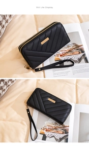 Detail of black quilted long wallet with gold hardware and secure wrist strap