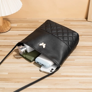 Quilted black bucket bag with gold butterfly accent showing spacious interior items