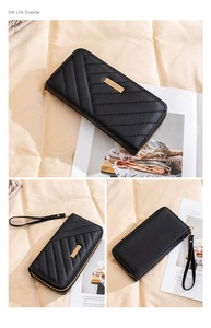 Detail of black quilted long wallet with golden metal plate and wrist strap accessory