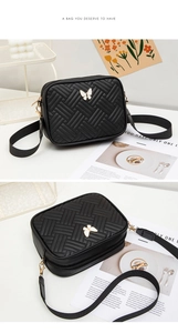 Détail d'un sac bandoulière noir tissé avec un fermoir en métal en forme de papillon blanc
