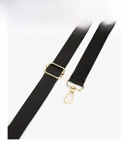 Detail of adjustable black nylon shoulder strap with polished gold metal buckles and hooks