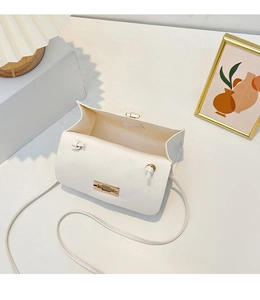 Detailed interior compartment view of a white quilted crossbody bag with gold lock hardware