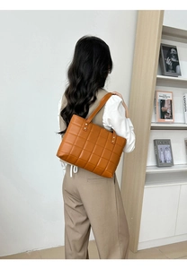Détail du sac cabas matelassé en similicuir caramel avec clous dorés porté à l'épaule